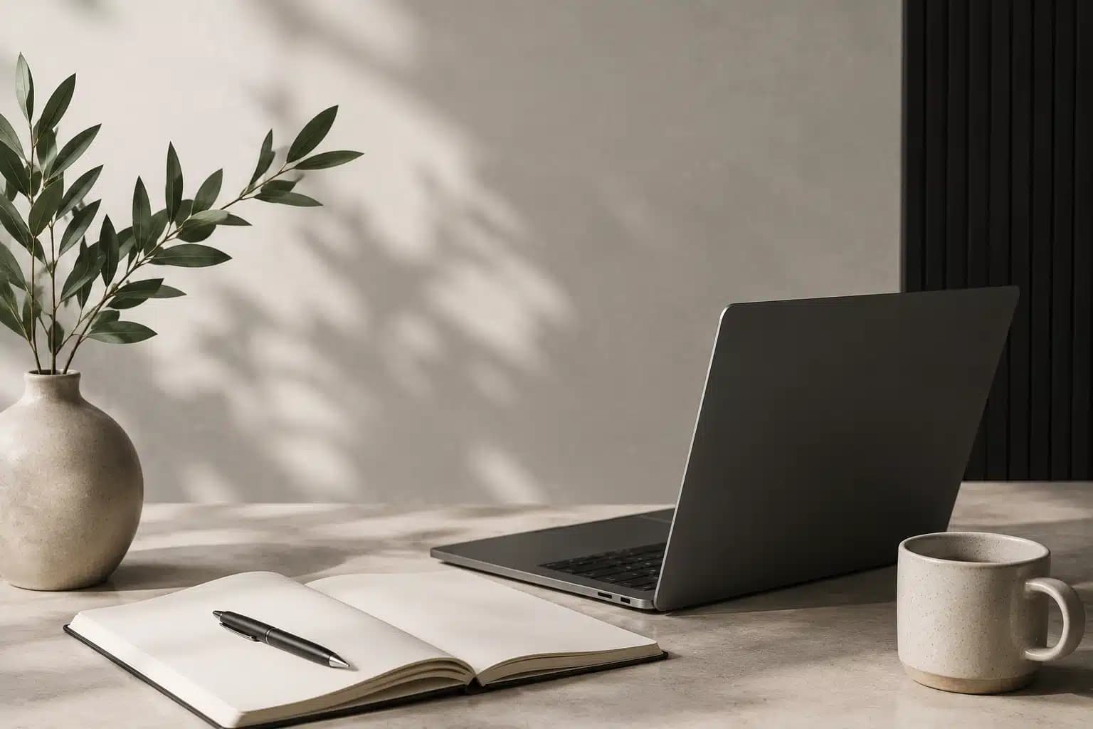 Laptop, notebook, plant, and coffee cup on a calm workspace desk