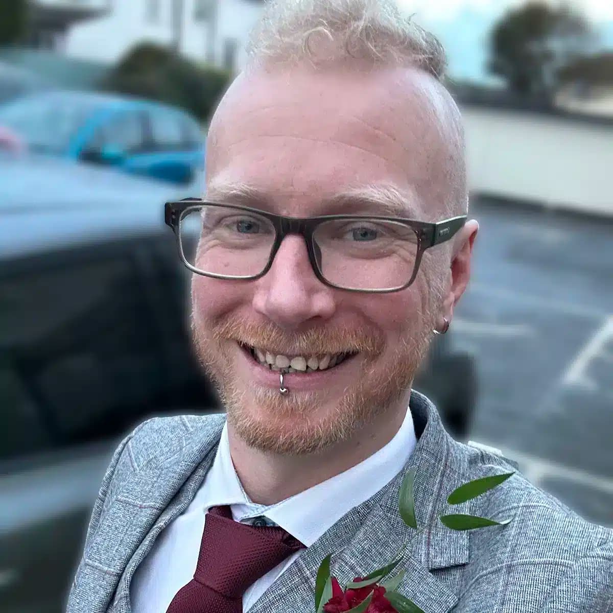Danny Prince-Brand smiling in a suit jacket and glasses